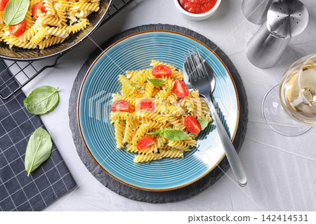 Delicious pasta with tomatoes and basil served on light table, flat lay Delicious pasta with tomatoes and basil served on light table, flat lay 142414531