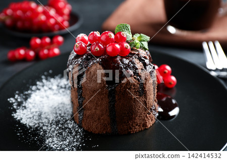 Delicious warm chocolate lava cake with mint and berries on plate, closeup Delicious warm chocolate lava cake with mint and berries on plate, closeup 142414532