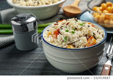 Delicious rice pilaf with chicken on black wooden table Delicious rice pilaf with chicken on black wooden table 142414687