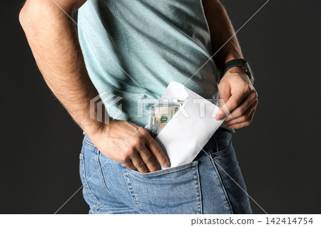Man putting bribe money into pocket on black background, closeup Man putting bribe money into pocket on black background, closeup 142414754