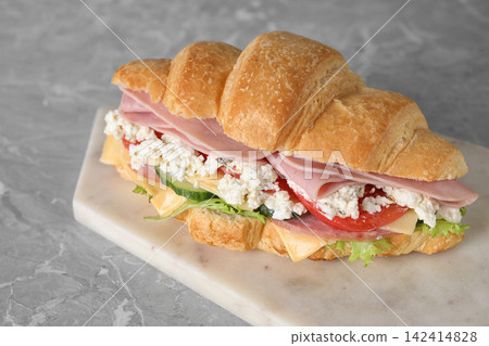 Tasty croissant sandwich with ham on grey marble table Tasty croissant sandwich with ham on grey marble table 142414828