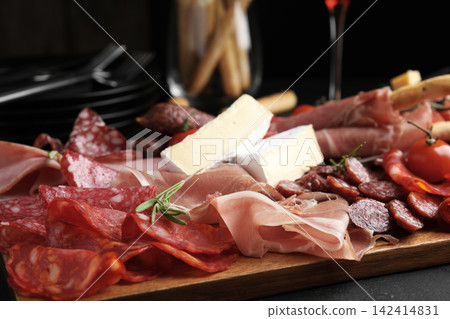 Tasty prosciutto with other delicacies served on black table, closeup Tasty prosciutto with other delicacies served on black table, closeup 142414831