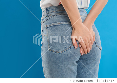 Woman suffering from hemorrhoid on light blue background, closeup Woman suffering from hemorrhoid on light blue background, closeup 142414857