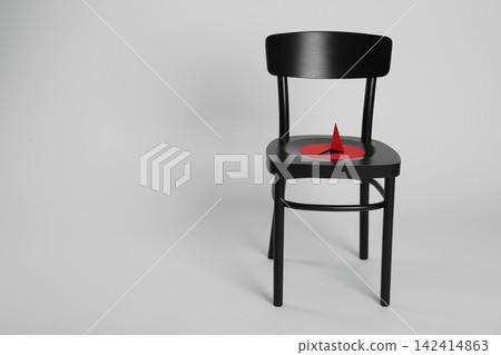 Chair with large red paper pin isolated on white. Hemorrhoids concept Chair with large red paper pin isolated on white. Hemorrhoids concept 142414863