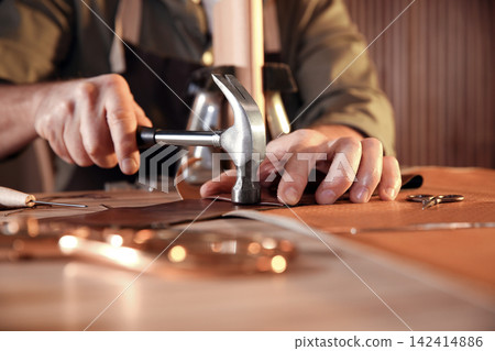Man working with piece of leather at table, closeup Man working with piece of leather at table, closeup 142414886