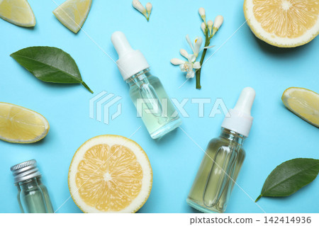Flat lay composition with bottles of citrus essential oil on light blue background Flat lay composition with bottles of citrus essential oil on light blue background 142414936