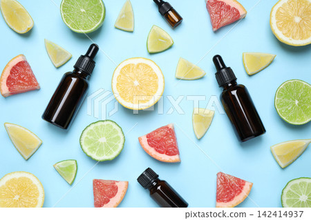 Flat lay composition with bottles of citrus essential oil on light blue background Flat lay composition with bottles of citrus essential oil on light blue background 142414937