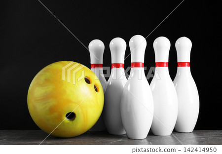 Yellow bowling ball and pins on grey stone table Yellow bowling ball and pins on grey stone table 142414950