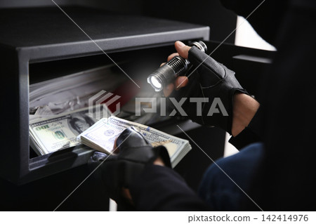 Thief taking money out of steel safe indoors, closeup Thief taking money out of steel safe indoors, closeup 142414976