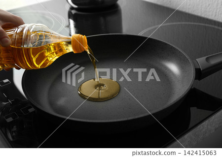 Woman pouring cooking oil from bottle into frying pan, closeup 142415063