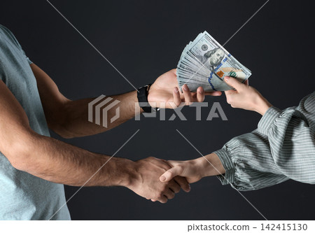 Woman shaking hands with man and offering bribe on black background, closeup 142415130