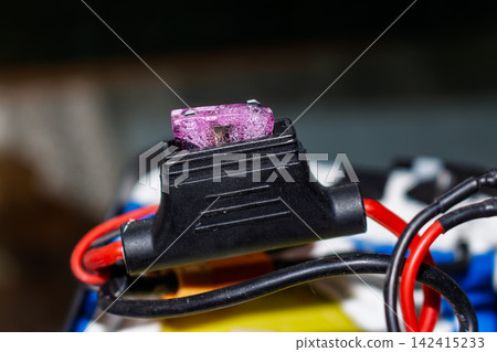 Close-up of a damaged, melted blade fuse from an electric bike battery pack, indicating a critical overheating issue and the urgent need for electrical component replacement and repair Close-up of a damaged, melted blade fuse from an electric bike battery pack, indicating a critical overheating issue and the urgent need for electrical component replacement and repair 142415233