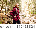 Woman hiking along a rocky trail surrounded by trees on a sunny day in the mountains 142415324