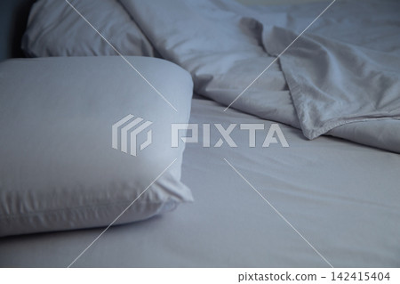 Side view of a bed with two pillows, covered with gray linens, the blanket is invitingly bent back, forming soft folds. The concept: an atmosphere of comfort and relaxation, going to bed. High quality Side view of a bed with two pillows, covered with gray linens, the blanket is invitingly bent back, forming soft folds. The concept: an atmosphere of comfort and relaxation, going to bed. High quality 142415404
