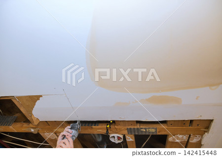 Contractor works on repairing drywall in home damage is seen above with multi tools used for fixing area. Contractor works on repairing drywall in home damage is seen above with multi tools used for fixing area. 142415448