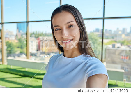 Young smiling female student looking at camera while taking selfie photo Young smiling female student looking at camera while taking selfie photo 142415603