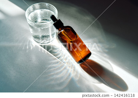 Skincare oil dropper bottle and glass of water Skincare oil dropper bottle and glass of water 142416118