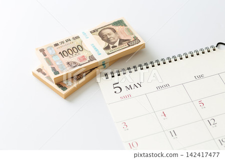 A May calendar and a stack of cash A May calendar and a stack of cash 142417477