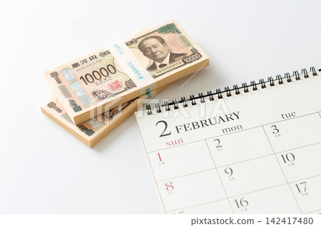 A February calendar and a stack of cash. A February calendar and a stack of cash. 142417480