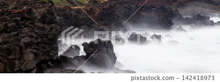 Dark Volcanic Rocks Surrounded by White Sea Foam and Crashing Waves on the Rugged Coast of Easter Island, Chile. Banner Web, Copy Space Dark Volcanic Rocks Surrounded by White Sea Foam and Crashing Waves on the Rugged Coast of Easter Island, Chile. Banner Web, Copy Space 142418973