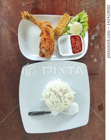 Indonesian fried chicken with rice and sambal on a wooden table in flat lay top view 142419082
