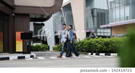Asian couple walking across pedestrian crosswalk in modern urban area during travel trip Asian couple walking across pedestrian crosswalk in modern urban area during travel trip 142419723