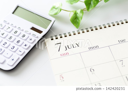July calendar and white calculator July calendar and white calculator 142420231