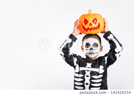 Halloween kid holding orange pumpkin bucket wearing spooky skeleton costume makeup standing isolated white background celebrating seasonal party festival happy childhood joy fun holiday spirit Halloween kid holding orange pumpkin bucket wearing spooky skeleton costume makeup standing isolated white background celebrating seasonal party festival happy childhood joy fun holiday spirit 142420254