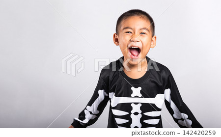 Halloween kid wearing skeleton costume shouting happily while celebrating spooky holiday festival on clean white isolated background for seasonal party concept Halloween kid wearing skeleton costume shouting happily while celebrating spooky holiday festival on clean white isolated background for seasonal party concept 142420259