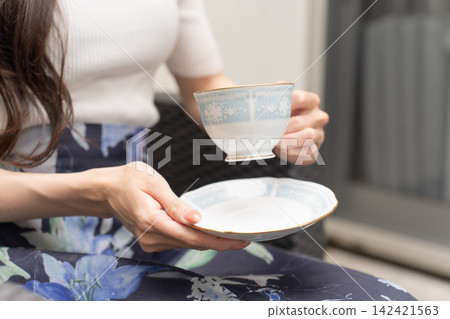A young woman holding a coffee cup on a terrace A young woman holding a coffee cup on a terrace 142421563