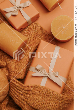 Candles and boxes on sweater on orange background, space for tex Candles and boxes on sweater on orange background, space for tex 142421769