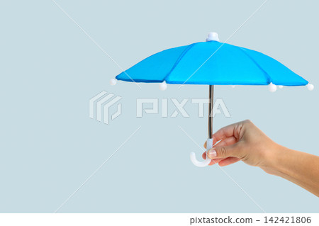 Insurance. Hand holds blue umbrella representing protection from risks Insurance. Hand holds blue umbrella representing protection from risks 142421806