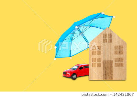 Insurance. Wooden house and red car placed under umbrella on yellow backdrop Insurance. Wooden house and red car placed under umbrella on yellow backdrop 142421807