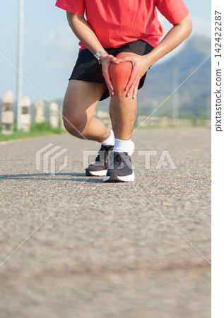 Young adult male runner with knee pain from ACL injury or patellofemoral syndrome. Man having joint ache, ligament tear or patellar tendinitis during running. Sports medical and healthcare concept Young adult male runner with knee pain from ACL injury or patellofemoral syndrome. Man having joint ache, ligament tear or patellar tendinitis during running. Sports medical and healthcare concept 142422287
