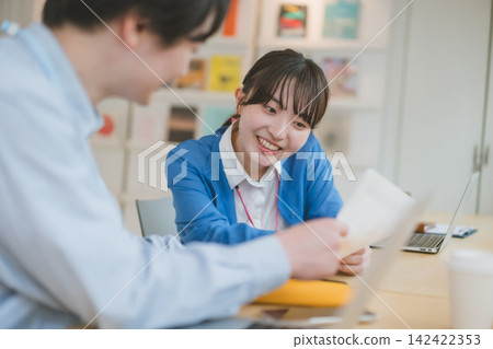Office work: A female employee receives documents at her desk and talks with a smile. Office work: A female employee receives documents at her desk and talks with a smile. 142422353