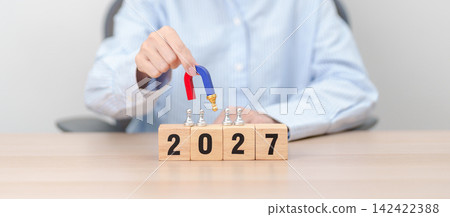 hand holding magnet and pulling man chess figure from the crowd employee with 2027 Year block. Human resource management, Recruitment, Teamwork, strategy, toxic people and leadership Concepts hand holding magnet and pulling man chess figure from the crowd employee with 2027 Year block. Human resource management, Recruitment, Teamwork, strategy, toxic people and leadership Concepts 142422388