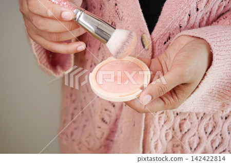 Applying blush with makeup brush indoors 142422814