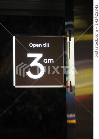 Open sign showing hours in a city at night Open sign showing hours in a city at night 142422842