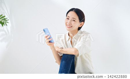 A middle-aged woman looking at her smartphone. Smartphone, apps, social media, videos, games, internet, points, coupons. A middle-aged woman looking at her smartphone. Smartphone, apps, social media, videos, games, internet, points, coupons. 142422880