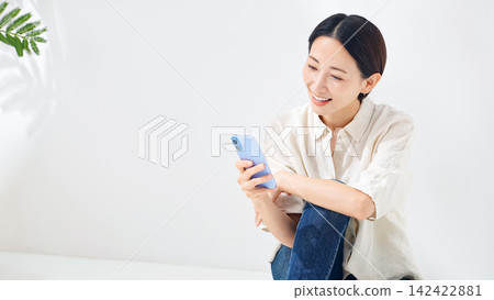 一位中年婦女正在看她的智慧型手機。智慧型手機、應用程式、社群媒體、影片、遊戲、網路、積分、優惠券。 142422881