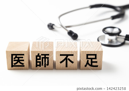 一塊寫著「醫生短缺」字樣的磚塊和一個聽診器。 142423258