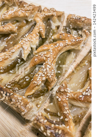 Freshly baked pear puff pastry tart with sesame seeds on wooden board Freshly baked pear puff pastry tart with sesame seeds on wooden board 142423499