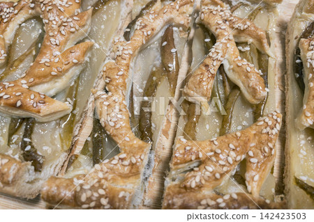 Freshly baked pear puff pastry tart with sesame seeds on wooden board Freshly baked pear puff pastry tart with sesame seeds on wooden board 142423503