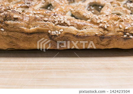 Macro shot of fresh sesame puff pastry crust on wooden board 142423504