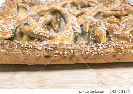 Macro shot of fresh sesame puff pastry crust on wooden board Macro shot of fresh sesame puff pastry crust on wooden board 142423505
