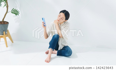 A middle-aged woman looking at her smartphone. Smartphone, apps, social media, videos, games, internet, points, coupons. A middle-aged woman looking at her smartphone. Smartphone, apps, social media, videos, games, internet, points, coupons. 142423643