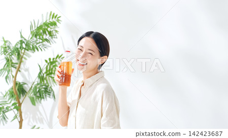 A woman drinking bottled tea. Hydration, oolong tea, green tea, black tea, barley tea, hydration, drinks, juice A woman drinking bottled tea. Hydration, oolong tea, green tea, black tea, barley tea, hydration, drinks, juice 142423687
