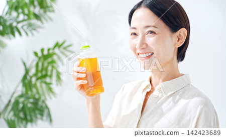 一位女士正在喝瓶裝茶。補水、烏龍茶、綠茶、紅茶、大麥茶、補水、飲料、果汁 一位女士正在喝瓶裝茶。補水、烏龍茶、綠茶、紅茶、大麥茶、補水、飲料、果汁 142423689