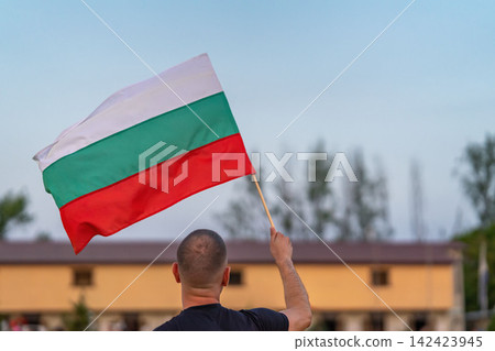 Bulgarian Flag Held by Man Outdoors. Man waving national flag of Bulgaria outdoors. Bulgarian identity, national celebration, patriotism, citizenship, country symbolism Bulgarian Flag Held by Man Outdoors. Man waving national flag of Bulgaria outdoors. Bulgarian identity, national celebration, patriotism, citizenship, country symbolism 142423945