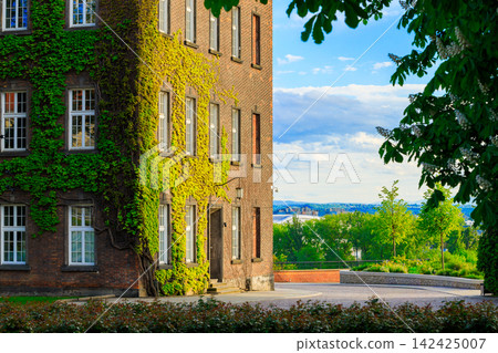 Charming European courtyard with ivy-covered brick building and lush garden Charming European courtyard with ivy-covered brick building and lush garden 142425007